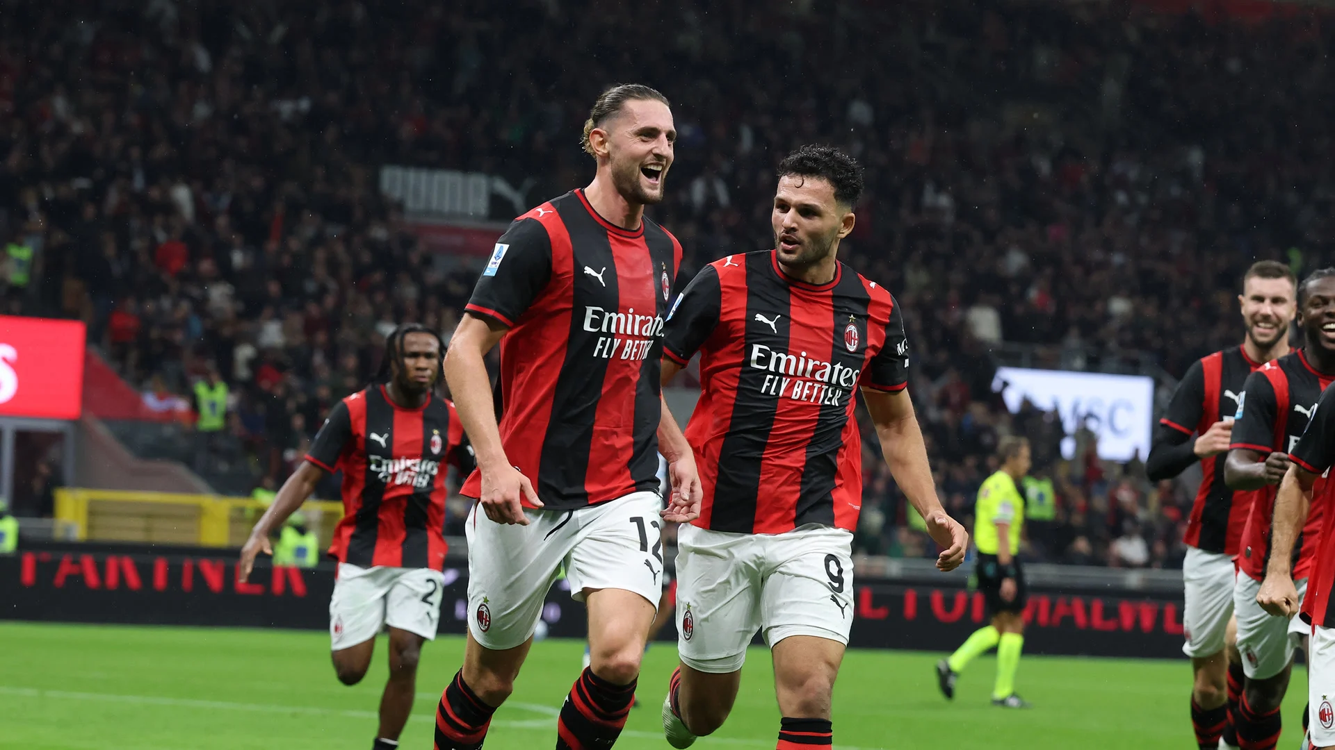 Adrien Rabiot (No 12) celebrates with Gonçalo Ramos (No 9), both in AC Milan's red and black striped home kit, during Milan's 3-2 Serie A win over Atalanta at San Siro, with team-mates following behind. Photo: AC Milan
