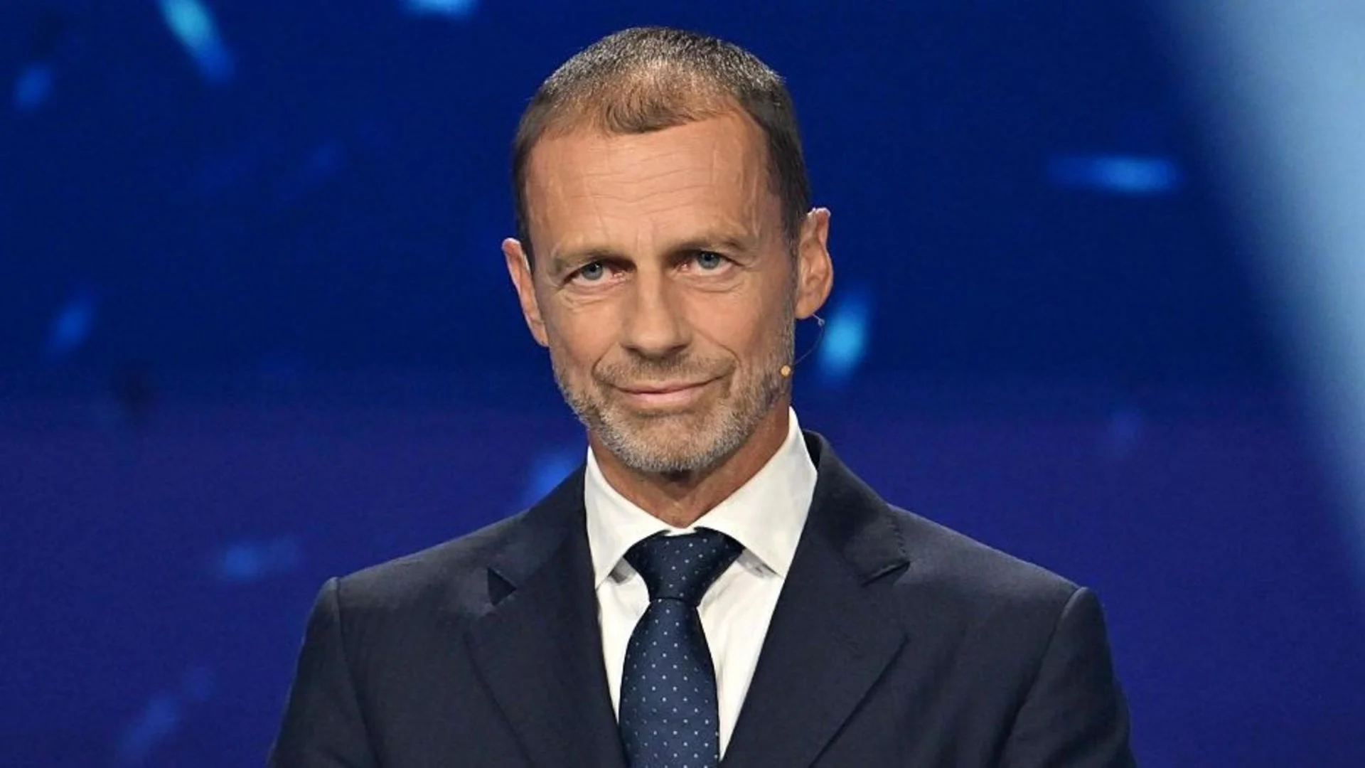 UEFA president Aleksander Čeferin, in a dark suit and blue tie, on stage at a UEFA event