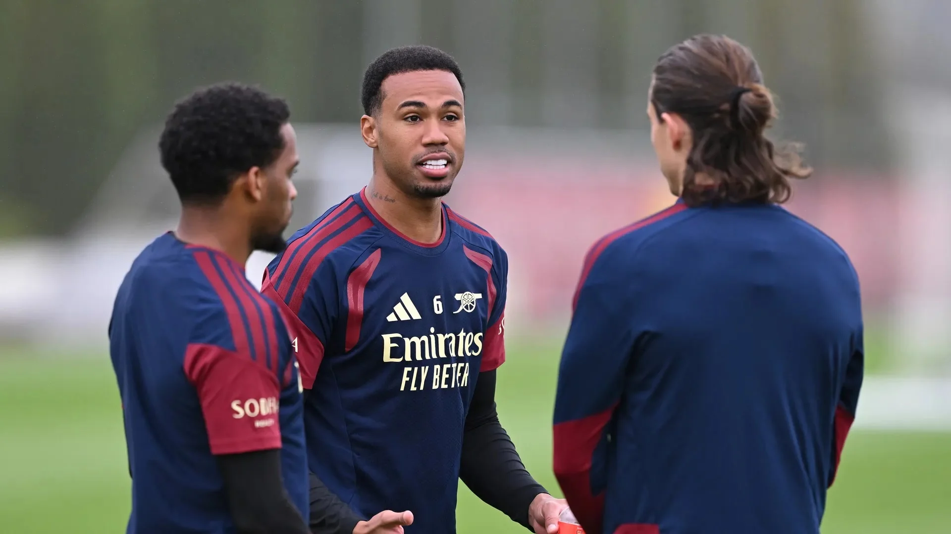 Arsenal defender Gabriel, wearing the number 6 navy-and-red Arsenal training top, talks with two team-mates during a training session at the Sobha Realty Training Centre.