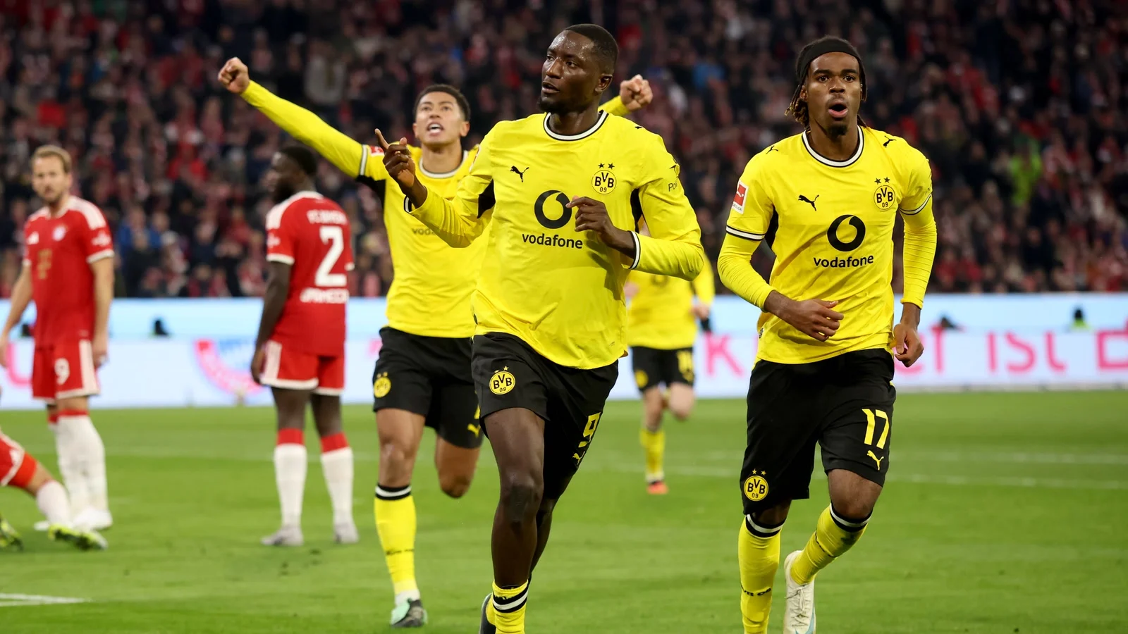 Serhou Guirassy celebrates his equaliser in Borussia Dortmund's yellow kit with team-mates, including Carney Chukwuemeka, as Bayern Munich players look on at the Allianz Arena