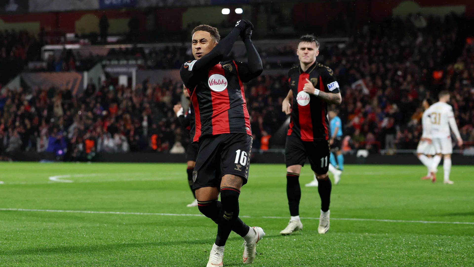 Marcus Tavernier, in Bournemouth's red and black striped home kit with the number 16, celebrates scoring his penalty against AC Milan at the Vitality Stadium, with team-mate Ben Gannon-Doak (number 11) behind him and AC Milan players in white in the background. Photo: Alex Pantling - UEFA/UEFA via Getty Images