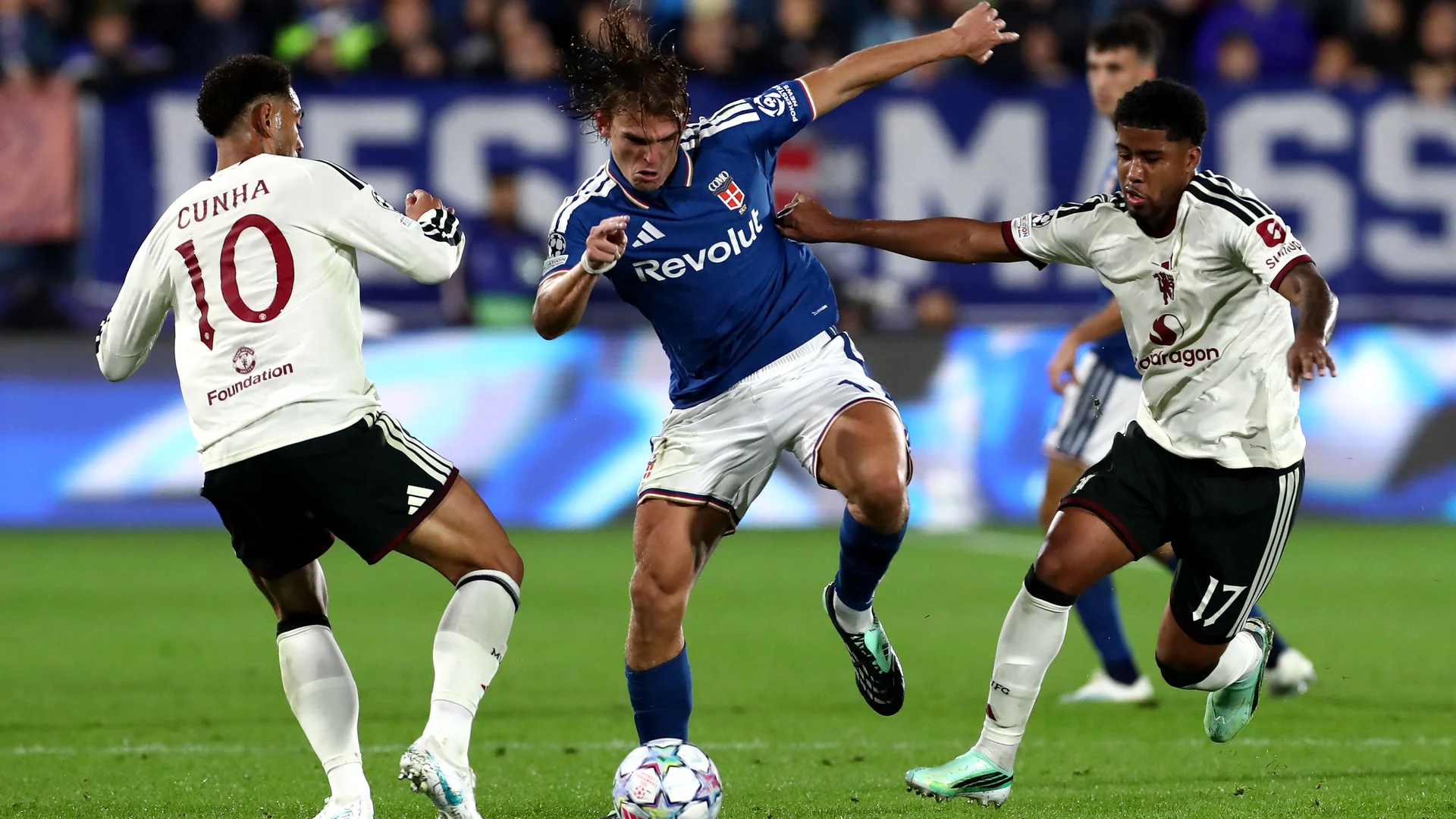 Nico Paz, in Como's blue home shirt and white shorts, holds off Manchester United's Matheus Cunha (number 10) and Andrey Santos (number 17), both in United's white away kit, at the Stadio Giuseppe Sinigaglia. Photo: Marco Luzzani/Getty Images