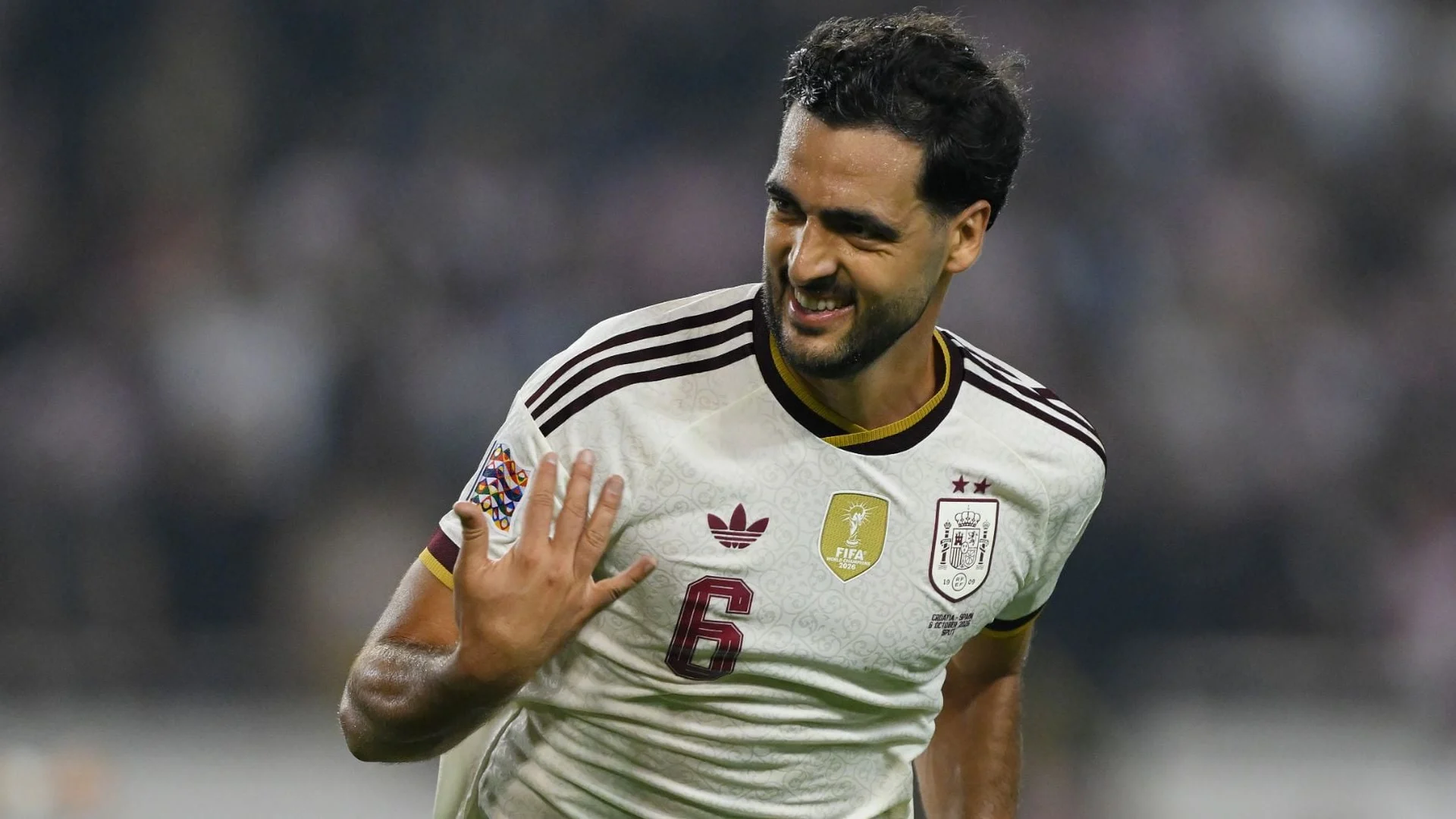 Mikel Merino, in Spain's white number 6 away shirt, smiles and gestures with his hand as he celebrates scoring against Croatia in Split (Photo: Getty Images via OKDiario)