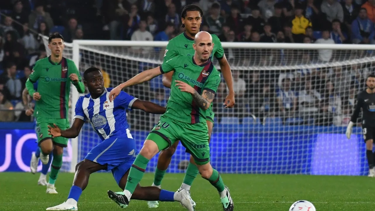 Levante's Oriol Rey, in the green away kit, holds off a Deportivo player in the blue-and-white striped home kit during Deportivo v Levante at Riazor on 16 October 2026. Photo: La Opinión A Coruña