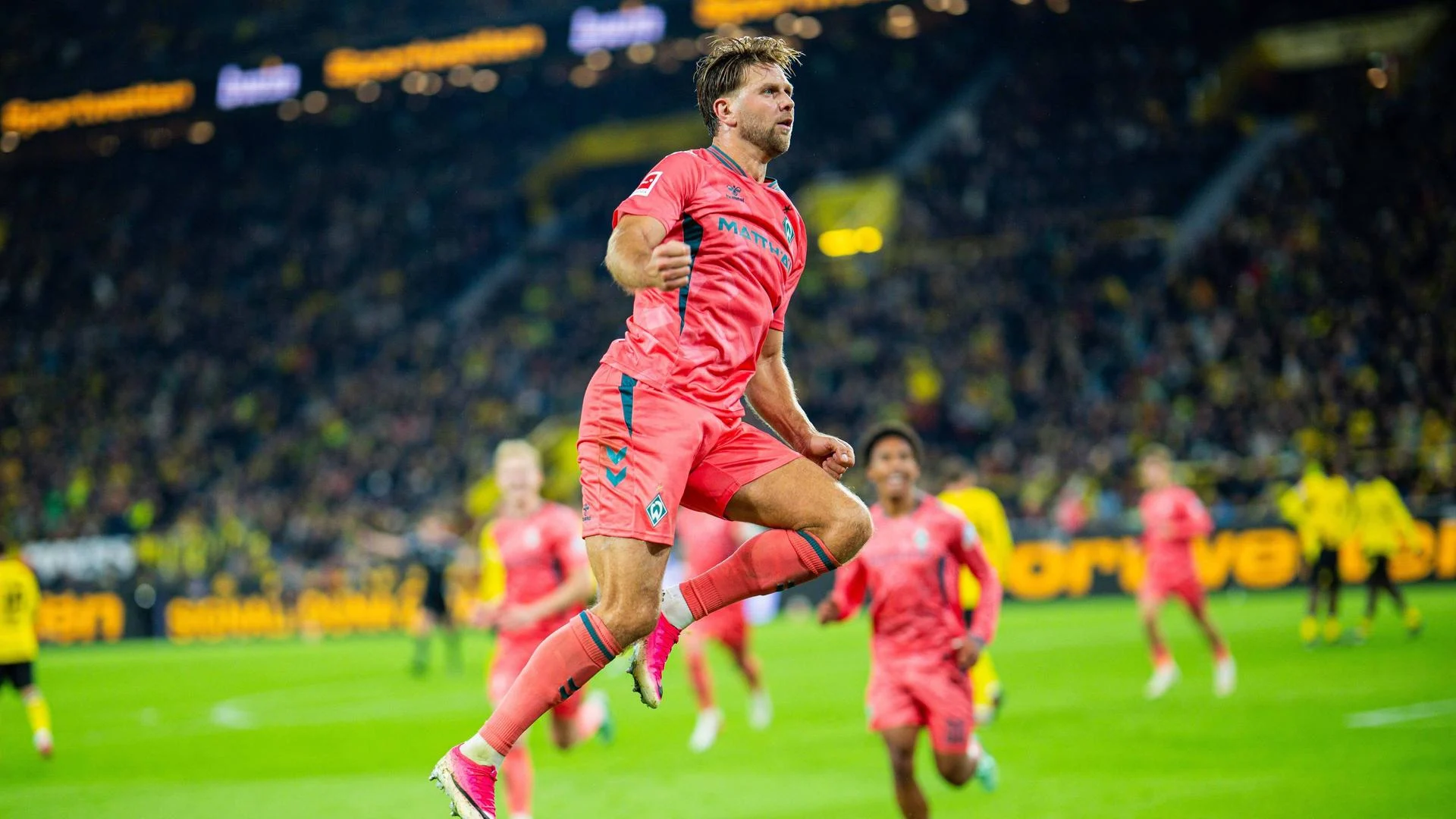 Niclas Füllkrug celebrating in a salmon Werder Bremen kit at Signal Iduna Park