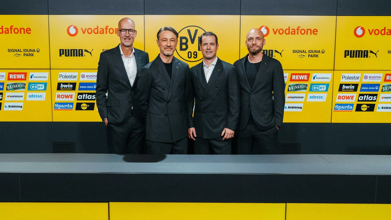 Dortmund head coach Niko Kovač, centre left in a dark suit, stands with club officials in front of the BVB press-room wall at Signal Iduna Park after signing his contract extension in October 2026. Photo: Borussia Dortmund