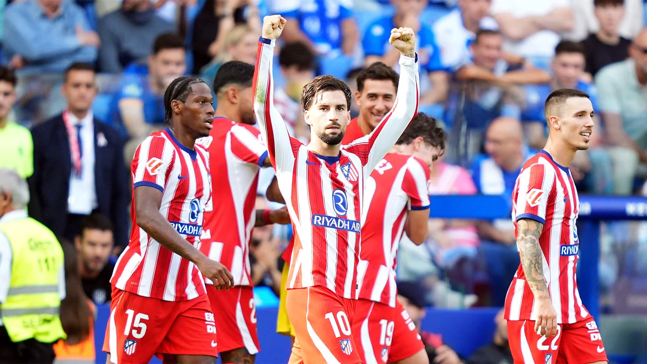Álex Baena raises both fists in Atlético Madrid's red-and-white striped home kit as team-mates celebrate his late winner against Espanyol at the RCDE Stadium. Photo: via AS.com