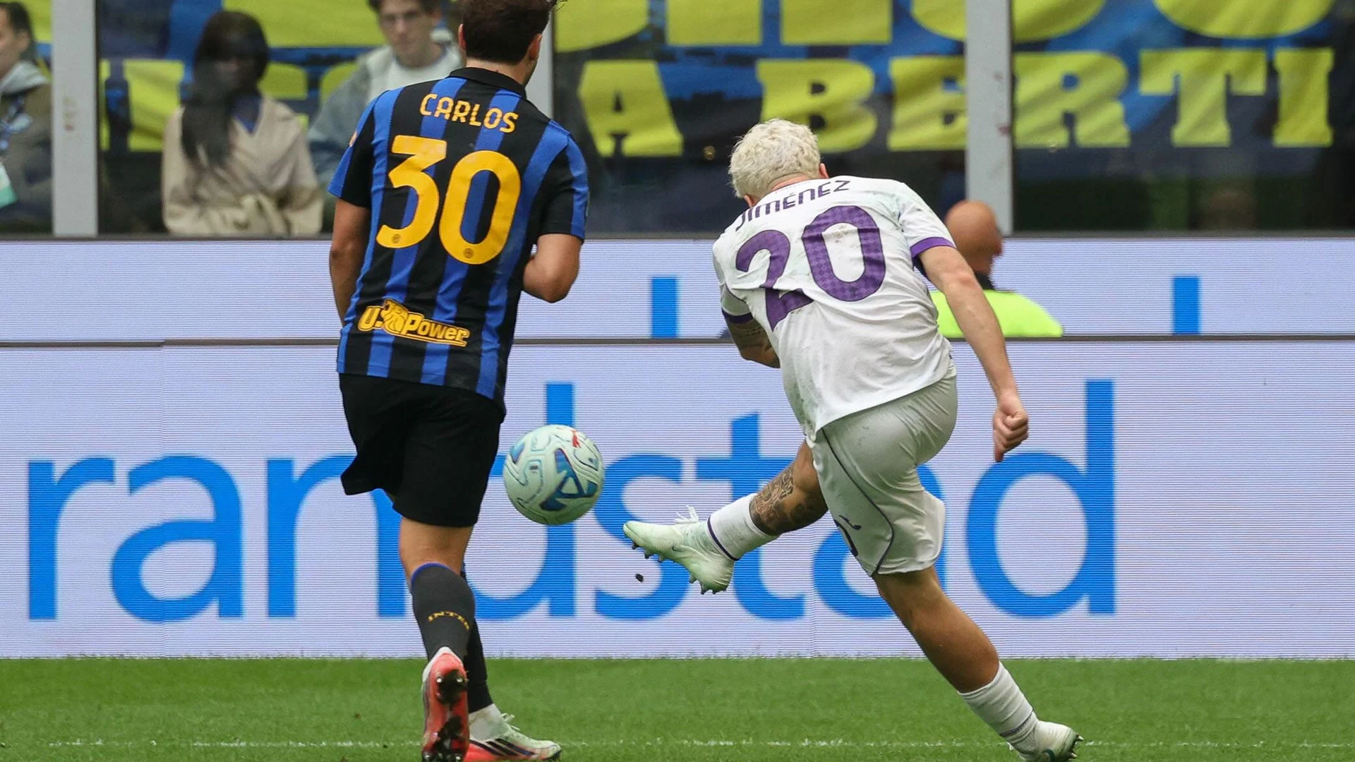 Fiorentina full-back Álex Jiménez, wearing Fiorentina's white kit with purple number 20, strikes the ball as Inter's Carlos Augusto, in Inter's blue-and-black No 30 shirt, looks on at San Siro on 25 October 2026. Photo: ANSA via Sky Sport