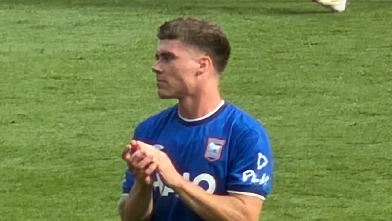 Ipswich Town left-back Leif Davis, wearing the club's blue 2026-27 home shirt, applauds on the pitch at the Premier League match against Sunderland at Portman Road on 22 August 2026. Photo: COYB123 / Wikimedia Commons, CC BY 4.0