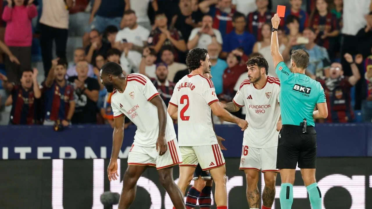 Referee Adrián Cordero Vega shows a red card to Sevilla's Isaac Romero, with Juan Iglesias beside him, at Levante's Ciutat de València. Photo: Ana Escobar/EFE