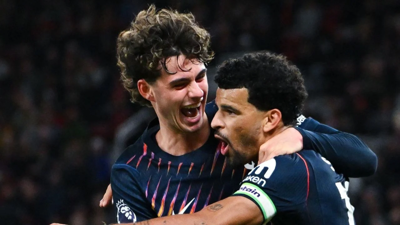 Dominic Solanke, wearing the captain's armband, celebrates his stoppage-time equaliser with Tottenham team-mate Archie Gray in the club's dark navy away kit at Old Trafford. Photo: via Sports Mole