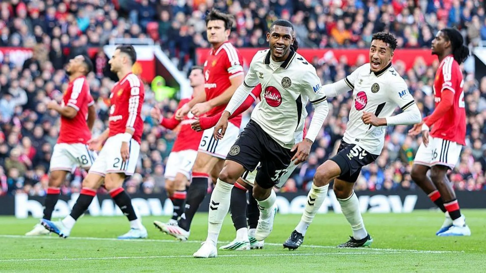 Bournemouth forward Rayan, in Bournemouth's white away shirt with black shorts (No 37), smiles as he celebrates during Bournemouth's 3-0 win over Manchester United at Old Trafford on 25 October 2026, with a Bournemouth team-mate running behind him and Manchester United players including Harry Maguire in red. Photo: Getty Images via BBC Sport