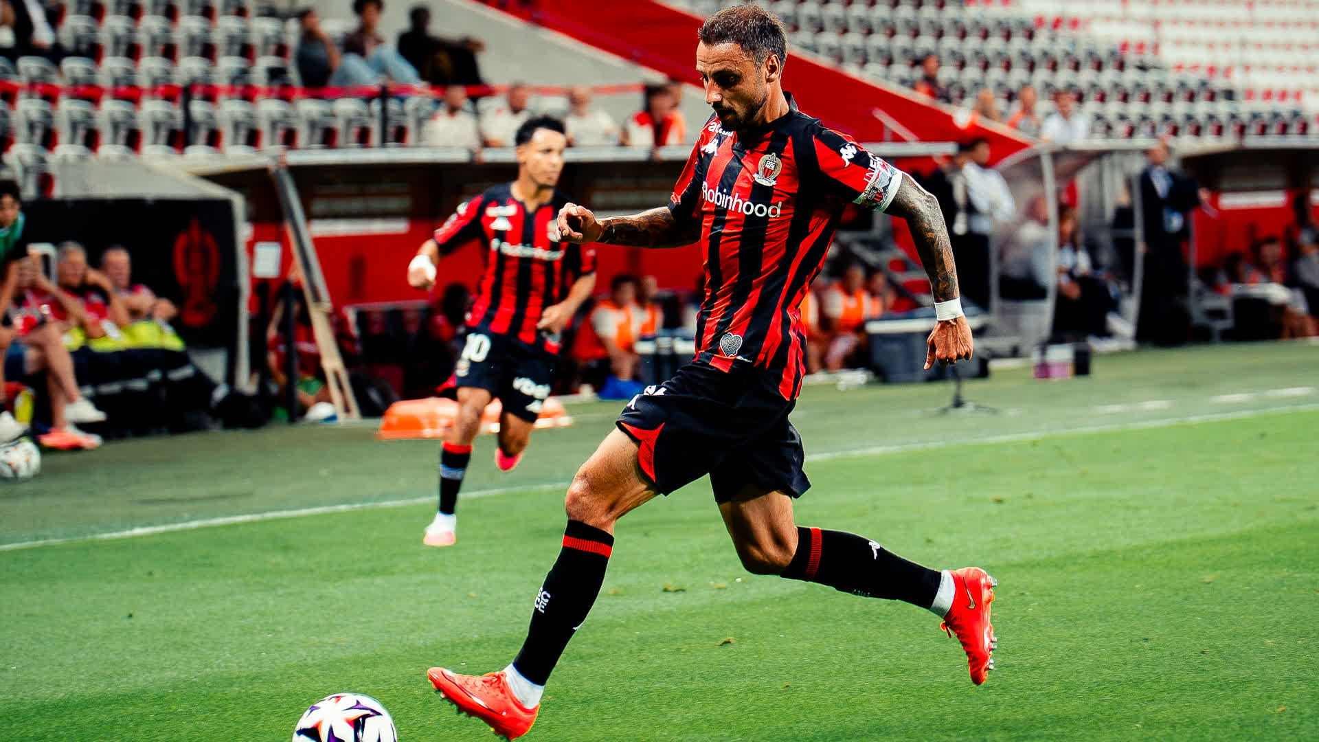 Jonathan Clauss in an OGC Nice red and black striped kit running with the ball