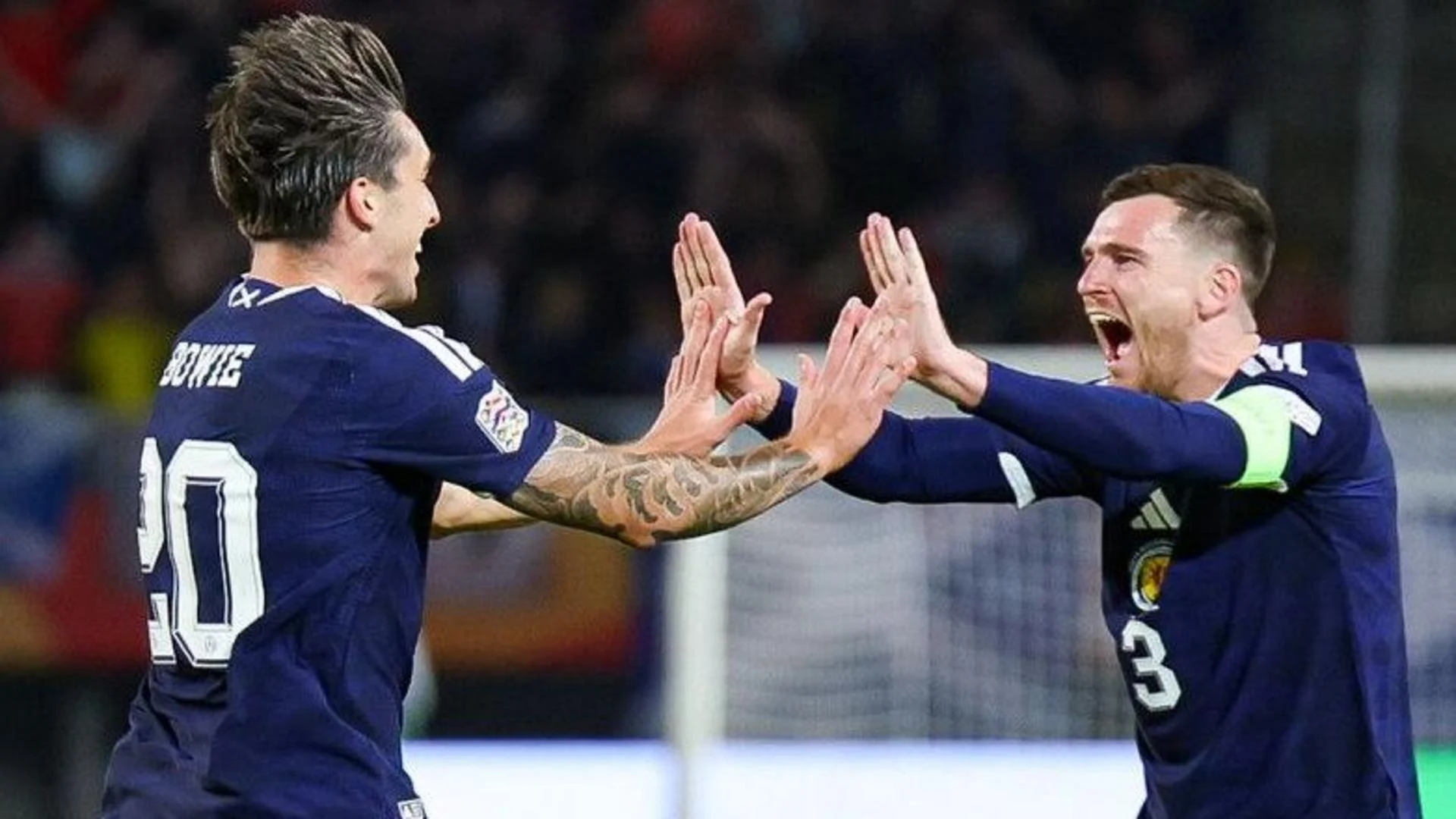 Kieron Bowie and captain Andy Robertson celebrate in dark blue Scotland shirts during the Nations League win away to North Macedonia in Skopje