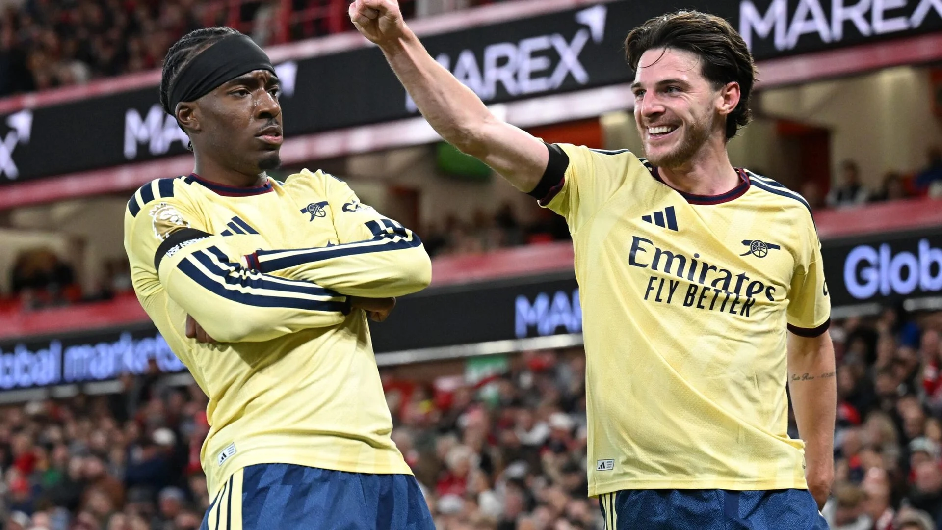 Arsenal's Declan Rice smiles and raises his fist as Noni Madueke stands with his arms folded after scoring the winner against Nottingham Forest at the City Ground, both in Arsenal's yellow away kit. Photo: Sky Sports
