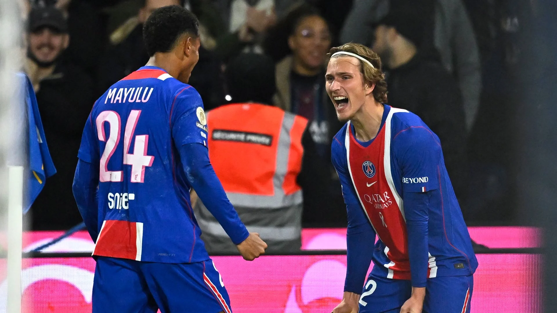 Senny Mayulu, wearing number 24, and Mika Godts celebrate in Paris Saint-Germain's blue home kit during the 2-0 Ligue 1 win over Lyon at the Parc des Princes on 26 October 2026. Photo: Julien de Rosa/AFP
