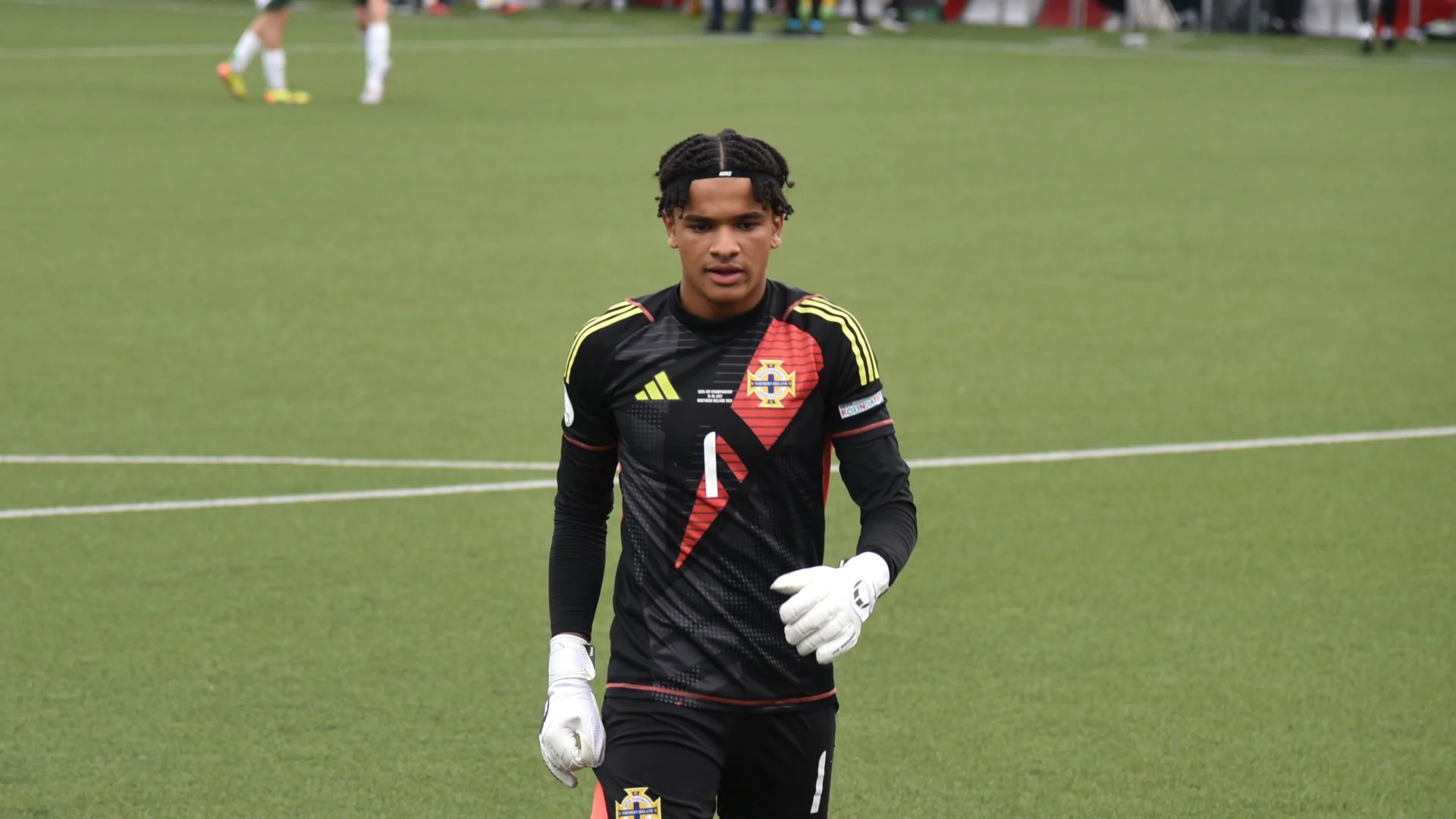 Goalkeeper Pierce Charles in a black Northern Ireland goalkeeper kit walking across the pitch during a match