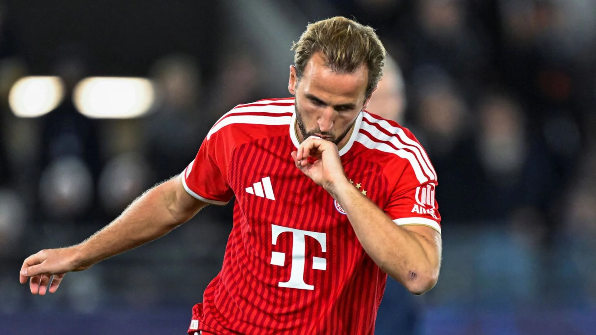 Harry Kane in Bayern Munich's red home kit kisses his thumb in celebration during the Champions League match at Lyse Arena. Photo: BBC Sport / Getty Images